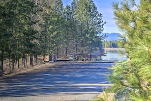 A road leading to a lakeside area with cabins and a dock. - Woodsy Riverfront Retreat in Trout Creek Montana! (Trout Creek)