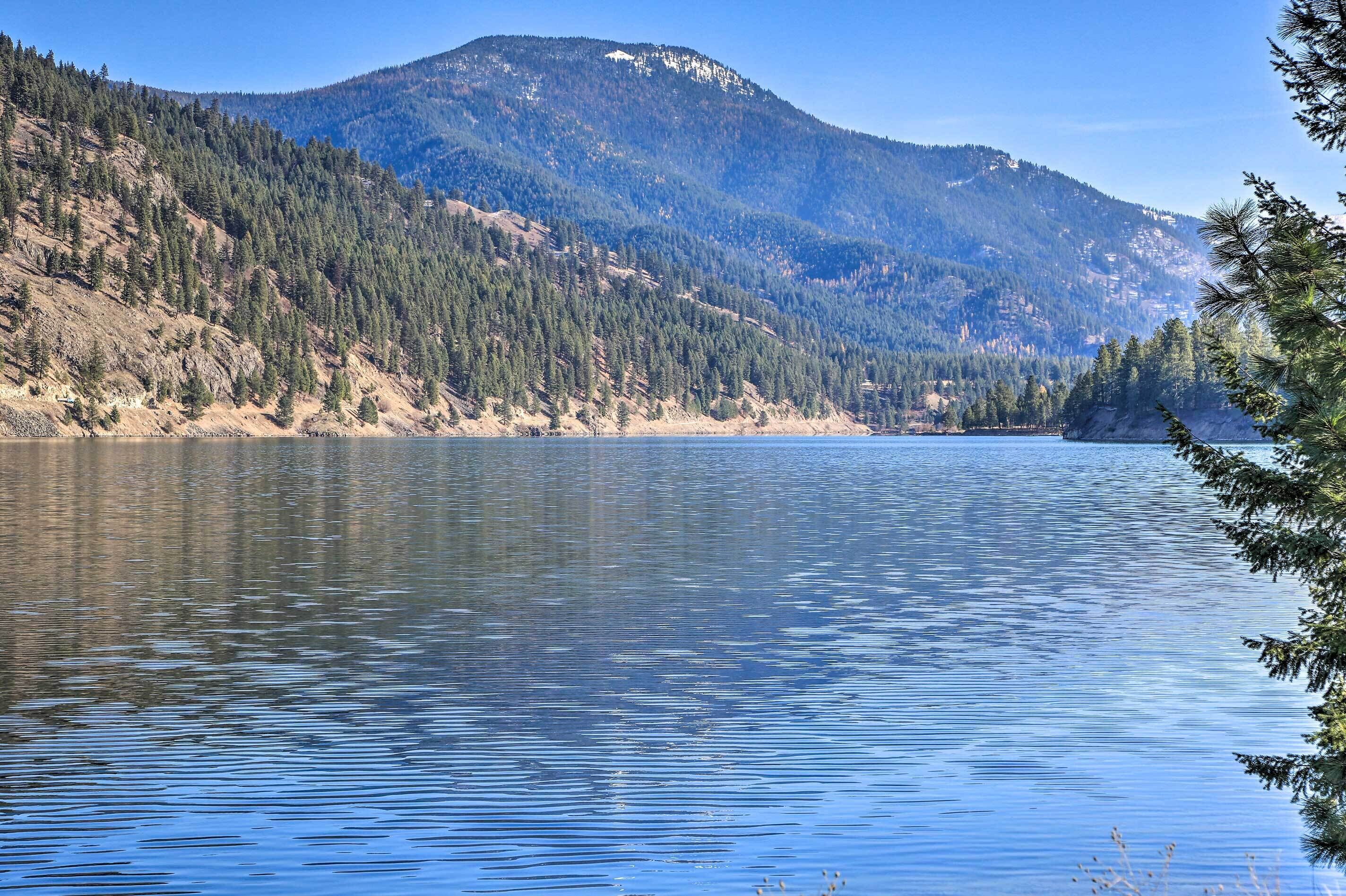 A calm lake with a forested mountain in the background.