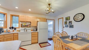 A kitchen with wooden cabinets, a white refrigerator, a stove, and a dining table with chairs.