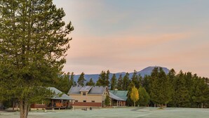 A lodge with a large open field, a building with a sloped roof, and a mountain in the background.