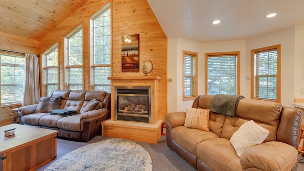 A cozy living room with a fireplace, leather sofas, and large windows.