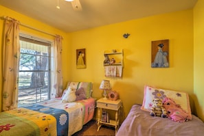 Une chambre avec deux lits, une fenêtre avec des rideaux, une table de chevet avec une lampe et des éléments de décoration murale.