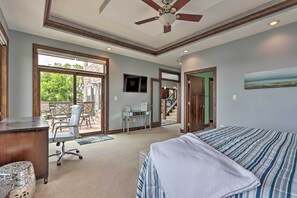 Une chambre à coucher avec un lit, un bureau et une chaise. On y trouve également un ventilateur de plafond, une télévision et une fenêtre.