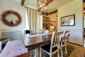 A dining area with a wooden table, white chairs, a chandelier, a mirror, and a framed map on the wall. - On-site Pond: Spacious Family Home in Jefferson! (Jefferson)