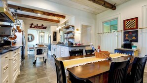 A kitchen with a central island, white cabinetry, and a hanging pot rack. - On-site Pond: Spacious Family Home in Jefferson! (Jefferson)
