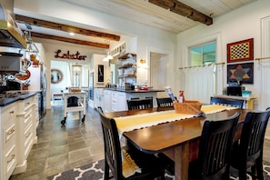 A kitchen with a central island, white cabinetry, and a hanging pot rack. - On-site Pond: Spacious Family Home in Jefferson! (Jefferson)