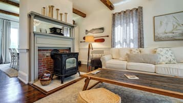 A cozy living room with a fireplace, a sofa, a coffee table, and nautical decor.