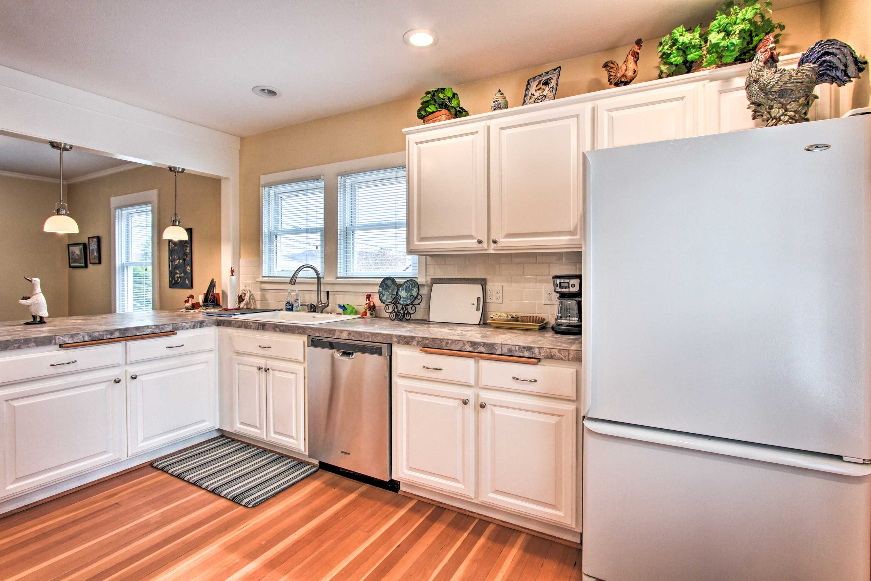 A modern kitchen with white cabinets, a stainless steel dishwasher, and a white refrigerator.