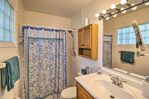A bathroom with a shower curtain, toilet, sink, and mirror. - Pet-friendly Sebastian Home on Lake; Golf Nearby (Sebastian)