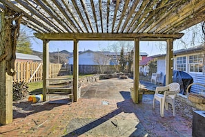 A covered patio area with a wooden pergola, a brick patio, and a white plastic chair. - Damascus Vacation Rental - Bike, Hike & Sip! (Damascus)