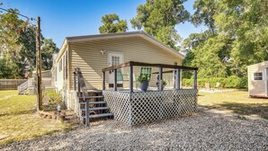 A single-story mobile home with a covered porch, a small outdoor seating area, and a gravel driveway. - 13 Mi to Silver Springs: Pet Friendly Getaway! (Silver Springs)