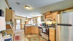 A kitchen with wooden cabinets, stainless steel appliances, and a patterned rug. - 13 Mi to Silver Springs: Pet Friendly Getaway! (Silver Springs)