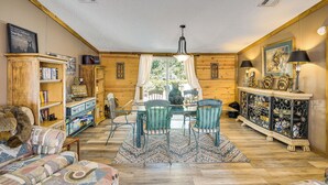 A cozy cabin interior with a dining table, chairs, a sofa, a bookshelf, and a decorative cabinet. - 13 Mi to Silver Springs: Pet Friendly Getaway! (Silver Springs)