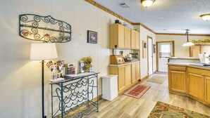 A kitchen with wooden cabinets, a white refrigerator, a metal console table with a lamp, and a decorative wall piece. - 13 Mi to Silver Springs: Pet Friendly Getaway! (Silver Springs)