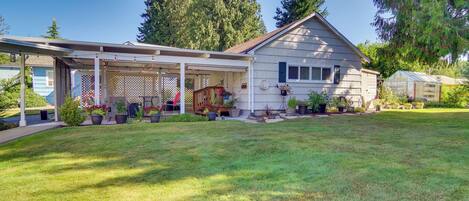 A two-story house with a covered porch, a small garden, and a greenhouse.
