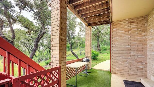 A covered patio area with a brick wall, a red wooden railing, and a grill table. - Relaxing Helotes Apt: 7 Mi to UT at San Antonio! (Helotes)