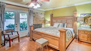 A bedroom with a wooden bed, a chair, a bench, a nightstand, and a ceiling fan. - Charming Lafayette Home ~ 5 Mi to Downtown! (Lafayette)