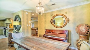 A dining area with a wooden table, chairs, a piano, and a large mirror on the wall. - Charming Lafayette Home ~ 5 Mi to Downtown! (Lafayette)