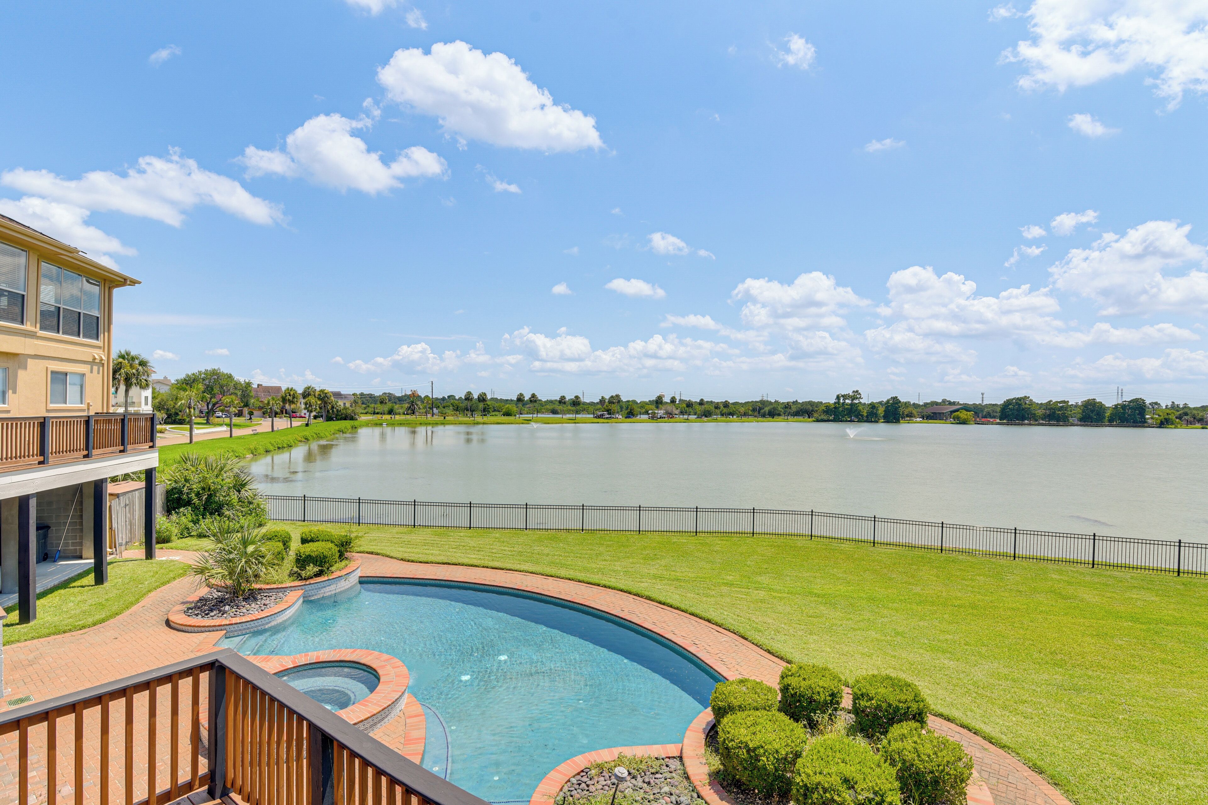 A residential area with a swimming pool, a view of a lake, and a two-story building with a balcony.