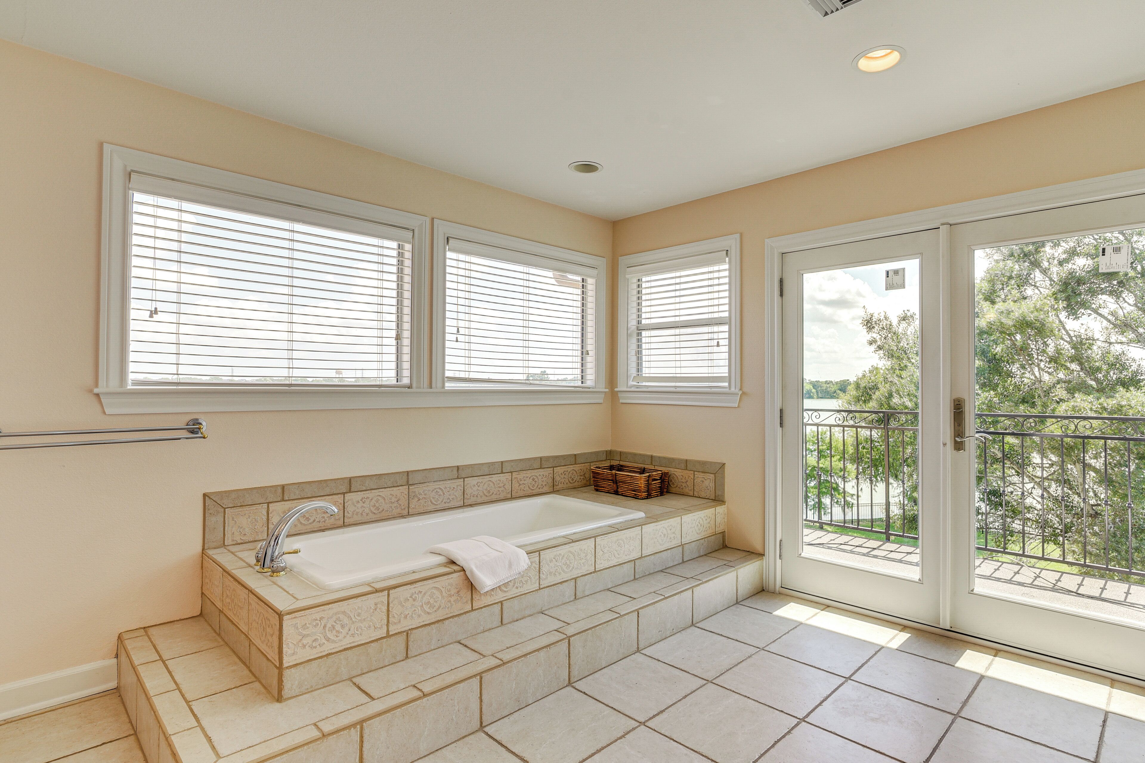 Un baño con bañera, ventana y puerta que da a un balcón.