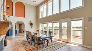 A spacious dining area with a large table and chairs, a stone floor, and a view of a deck through large windows. - Lakefront Houston House - 1 Mi to Space Center! (Houston)