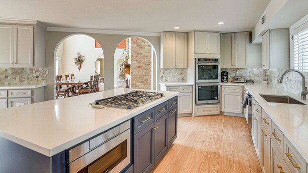 A modern kitchen with a large island, built-in appliances, and a dining area visible through an archway. - Lakefront Houston House - 1 Mi to Space Center! (Houston)