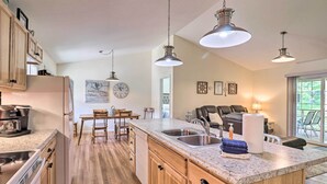 Une cuisine moderne avec des meubles en bois, un îlot central doté d’un évier et des luminaires suspendus.