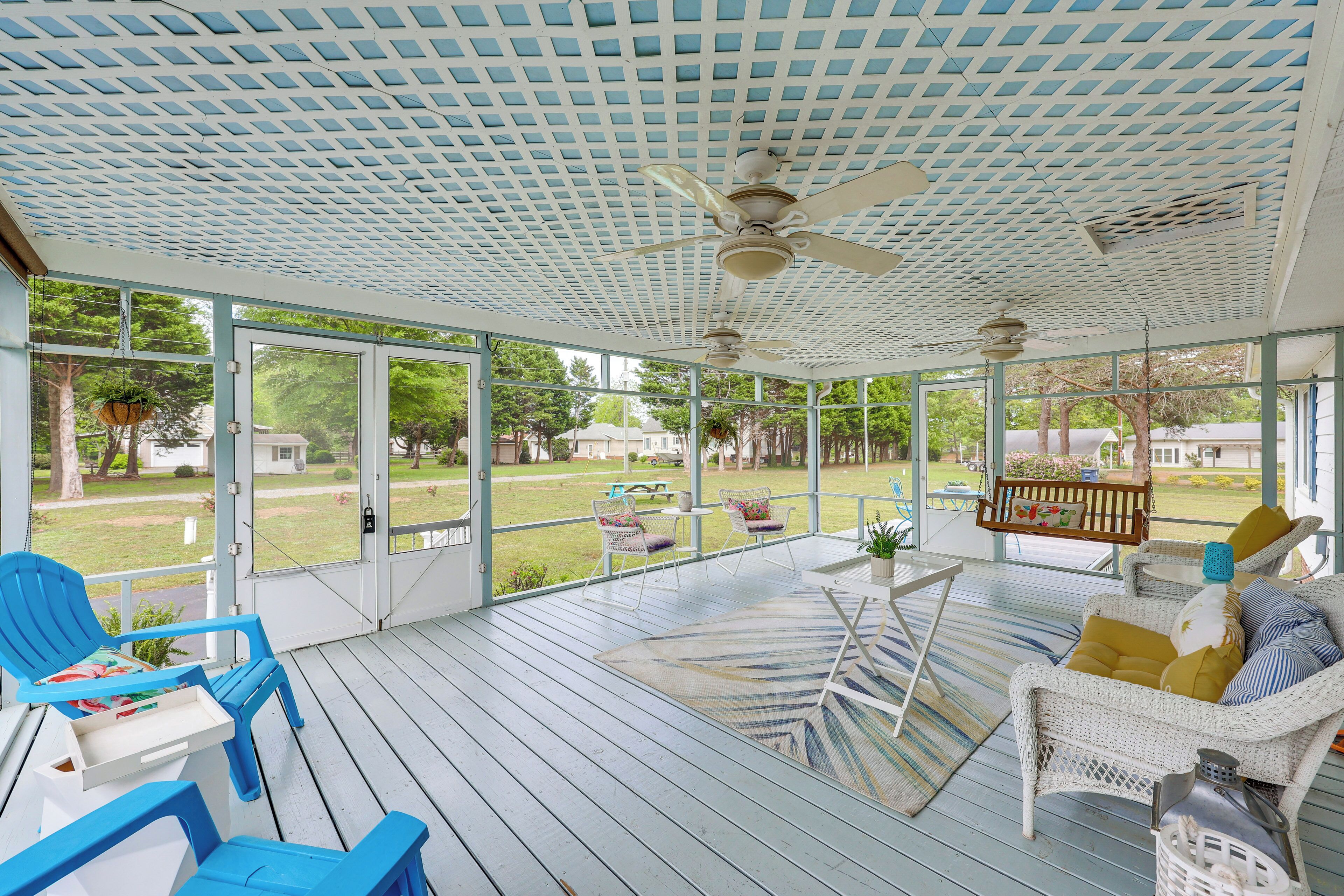 A covered porch with wicker furniture, a ceiling fan, and a view of the yard.