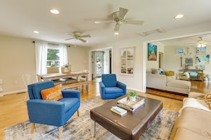 Un salon comprenant un canapé, des fauteuils, une table basse et un ventilateur de plafond.