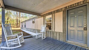 Een overdekte veranda met twee schommelstoelen en een deur.