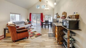 A spacious living area with a sofa, armchair, and dining table. A kitchen area with appliances and a wooden cabinet is visible. - Kalispell Cabin 28 Miles to Glacier National Park! (Kalispell)