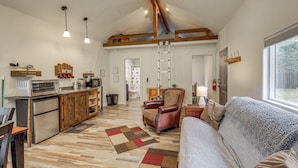 A spacious kitchen with wooden beams, a dining area with a sofa, and a large window. - Kalispell Cabin 28 Miles to Glacier National Park! (Kalispell)