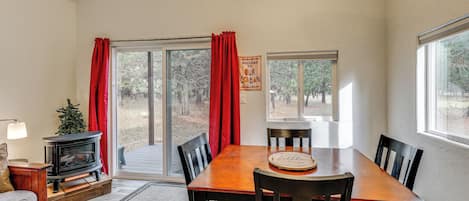 A dining area with a wooden table, chairs, a small Christmas tree, and a fireplace.
