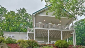 A two-story house with a balcony, surrounded by lush greenery and a well-maintained garden. - Guilford Lake Cottage w/ Hot Tub & Water Views (Lisbon)