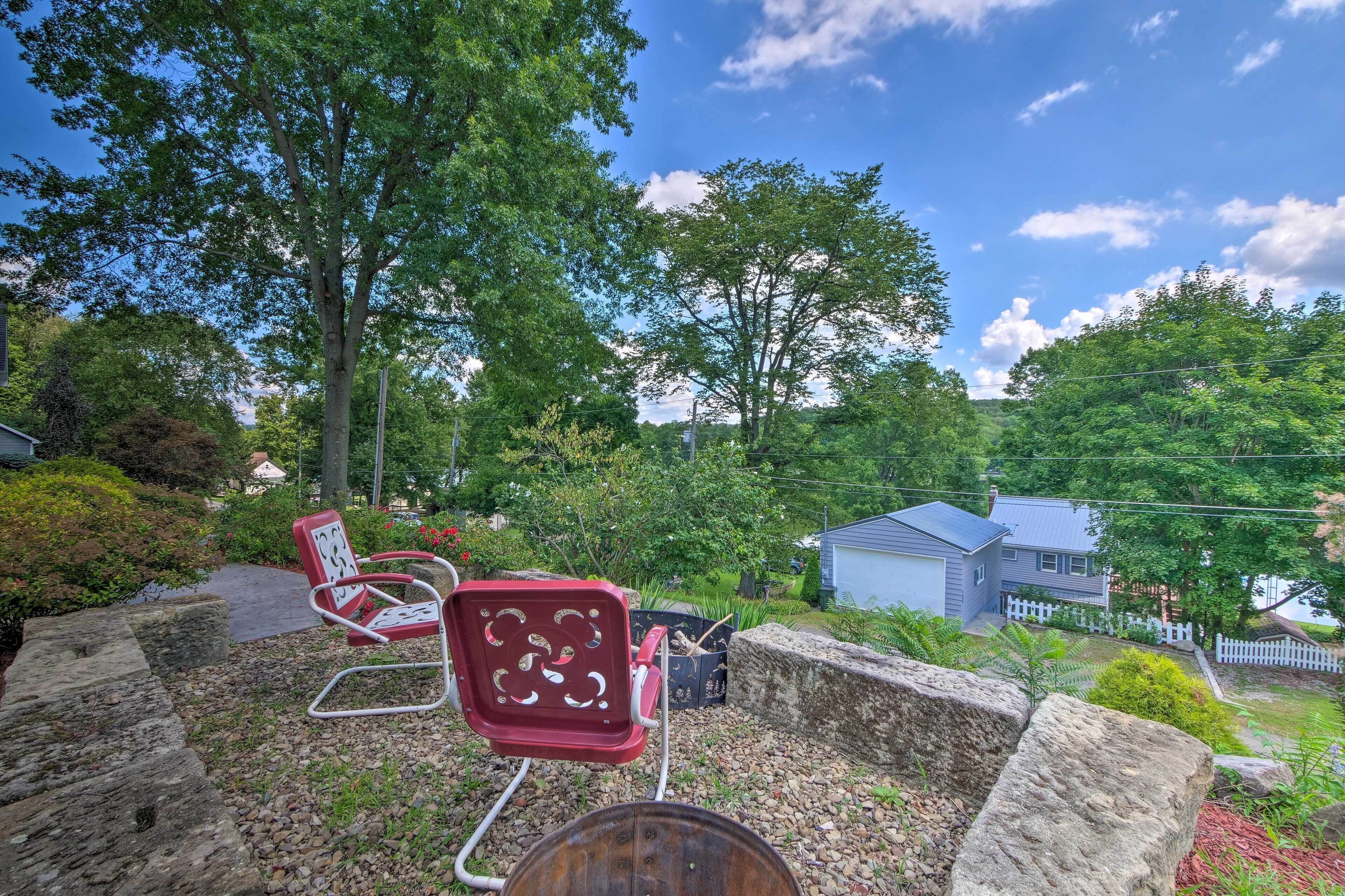 Un espace patio avec deux chaises rouges, une table en métal et un mur en pierre.