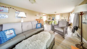 Ein gemütliches Wohnzimmer mit einer Couch, zwei Korbstühlen, einem Ventilator und einer Lampe.