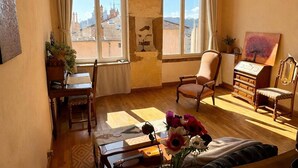 A room with a wooden floor, a dining table with chairs, a sofa, a wooden cabinet, and a painting on the wall. - Charming croix roussien apartment Lyon 1 (THIZY LES BOURGS)