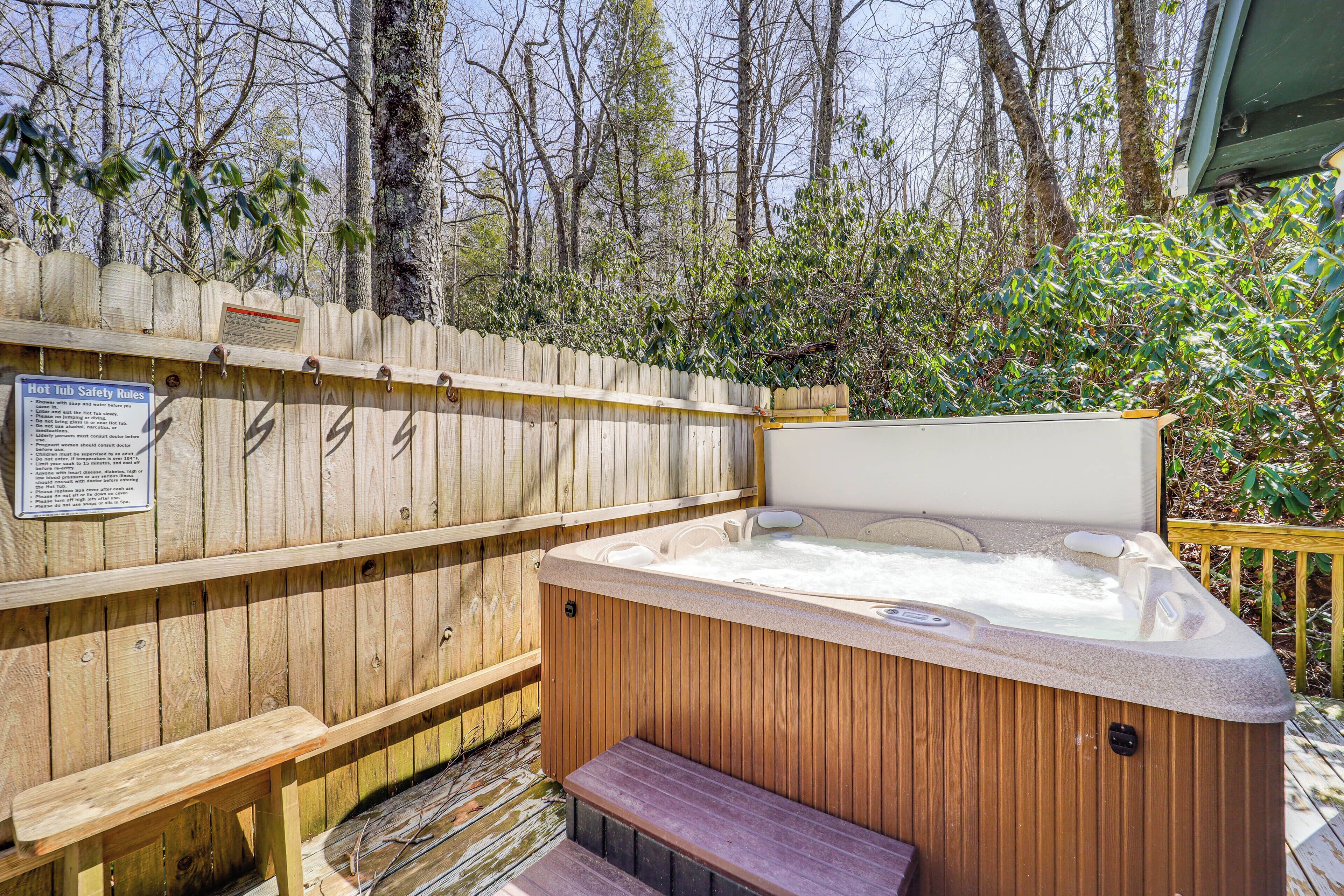 A hot tub with a wooden deck and a safety sign.