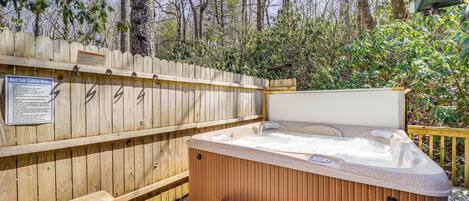 A hot tub with a wooden deck and a safety sign.