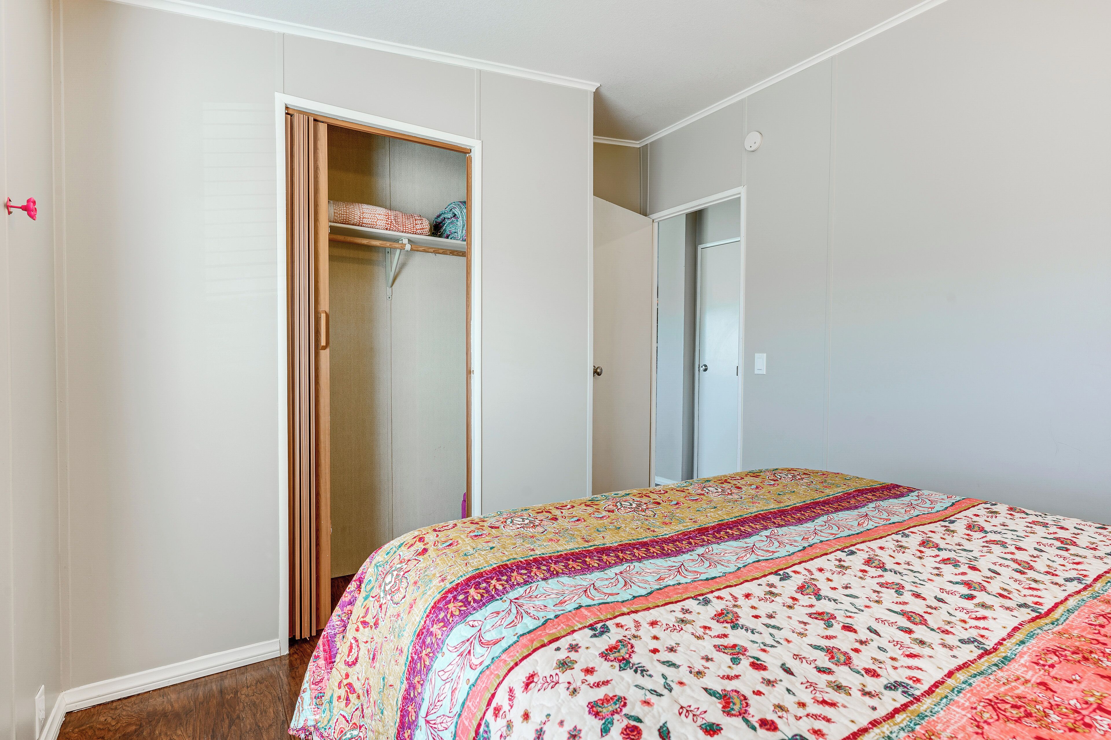 A bedroom with a bed, a wardrobe, and a door leading to another room.