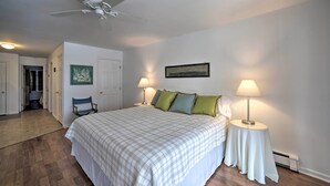 A bedroom with a bed, two bedside lamps, a ceiling fan, and a door leading to another room. - Bolton Landing Suite w/ Deck, Lake George Access (Bolton Landing)