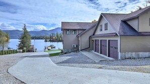 A two-story house with a garage, a driveway, and a lake view. - Bolton Landing Suite w/ Deck, Lake George Access (Bolton Landing)