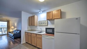 A modern kitchen with wooden cabinets, a white refrigerator, a microwave, and a dishwasher. - Bolton Landing Suite w/ Deck, Lake George Access (Bolton Landing)