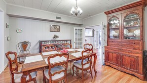 Una sala da pranzo con un tavolo in legno, sedie, un lampadario e una credenza.