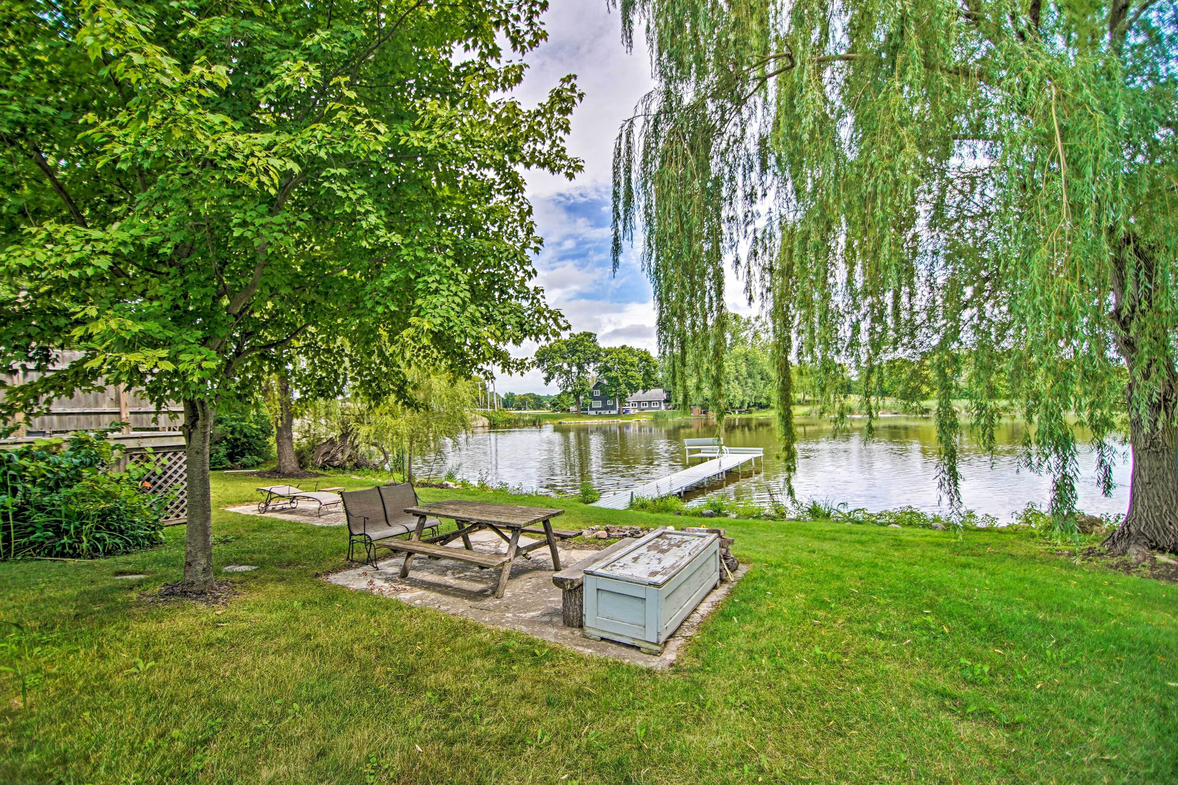 Un espacio de picnic junto al lago con banco, mesa y un cobertizo pequeño.