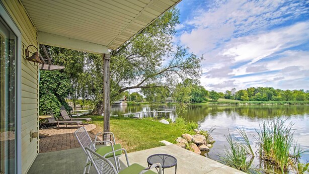 A covered patio with outdoor furniture, a pond, and a view of a lake and trees. - Rock River Access! Peaceful Horicon Studio (Horicon)