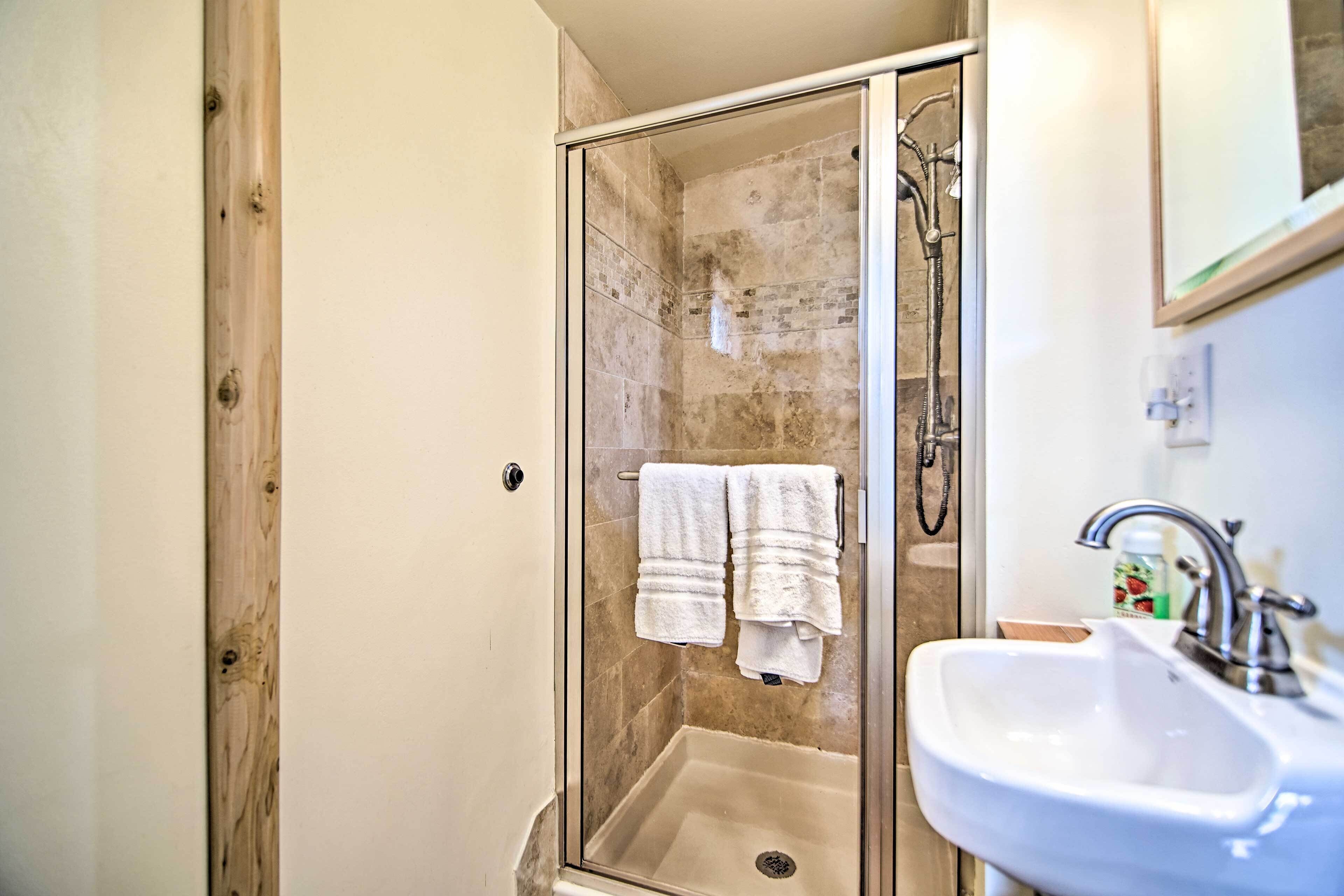 Une salle de bain avec une douche à parois de verre, un lavabo blanc et un miroir au-dessus du lavabo.