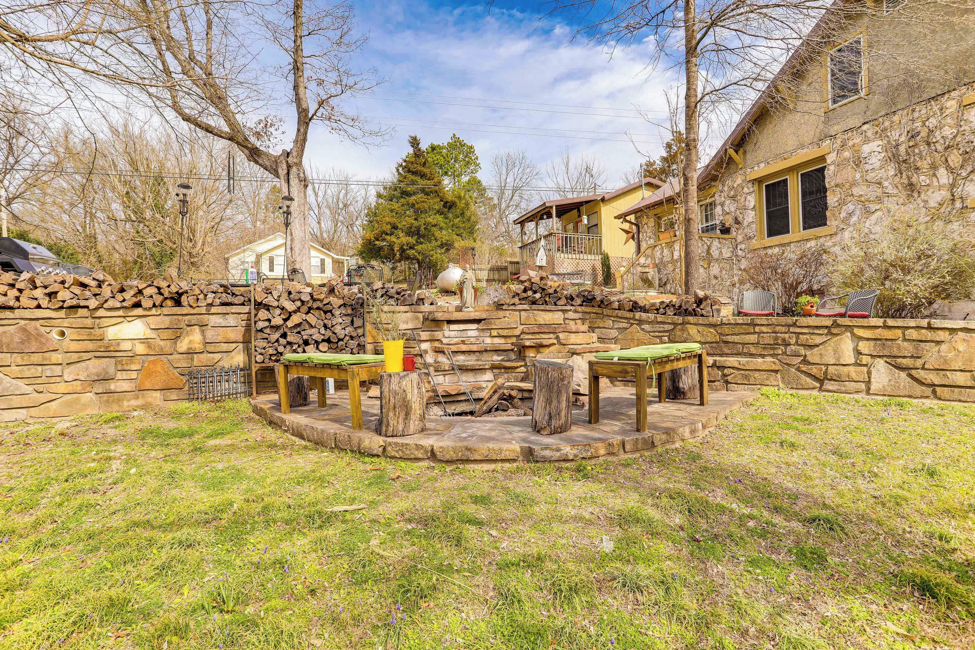 A stone patio with a fire pit, seating, and a stone wall.