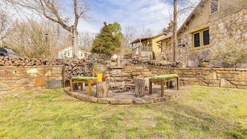 A stone patio with a fire pit, seating, and a stone wall.