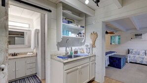 A modern kitchen with white cabinets, a built-in sink, and a countertop. There is a wooden ceiling fan and a window above the sink. - 'nantucket Cottage' w/ Fishing Dock + Sunsets (Fernandina Beach)